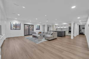 Living room with light wood-type flooring and recessed lighting