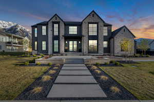 View of front of property with stone siding, a mountain view, and a front lawn