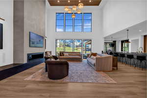 Living area featuring light wood finished floors, a glass covered fireplace, recessed lighting, and a high ceiling