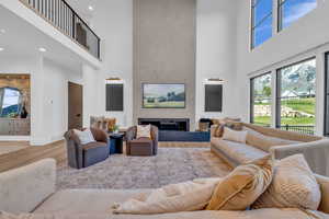 Living room featuring a glass covered fireplace, a high ceiling, and wood finished floors