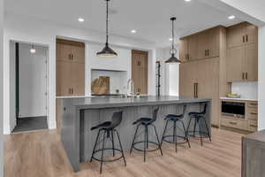 Kitchen with light wood finish cabinets, light wood-style floors, and dark stone counters