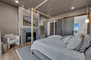 Bedroom with a glass covered fireplace, wood finished floors, and recessed lighting