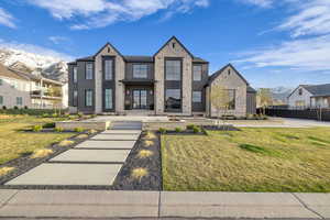 View of front facade featuring a mountain view, a front lawn, stone siding, and a residential view
