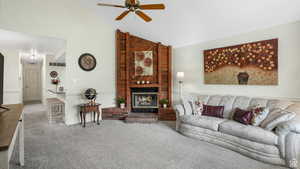 Living room with carpet flooring, ceiling fan, lofted ceiling, and a brick fireplace