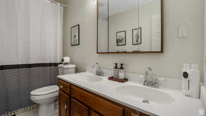 Full bath with double vanity, curtained shower, and light tile patterned floors