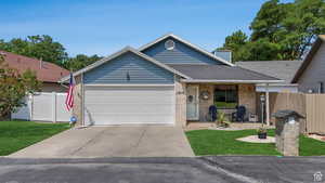 Ranch-style home with a porch, a garage, driveway, brick siding, and a chimney