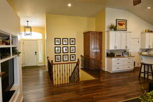 Kitchen featuring dark stone counters, white cabinetry, dark wood finished floors, tasteful backsplash, and suspended lighting