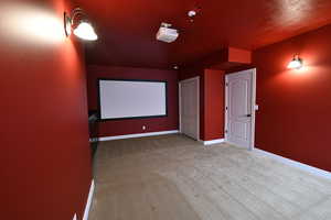 Home theater featuring light colored carpet and baseboards
