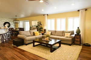 Living room with dark wood-type flooring, a ceiling fan, and a chandelier