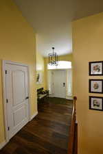 Foyer entrance featuring dark wood finished floors, a chandelier, and lofted ceiling