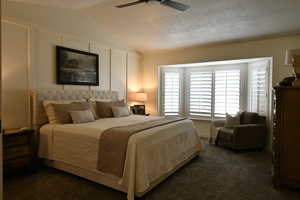Bedroom with dark carpet, vaulted ceiling, and a ceiling fan