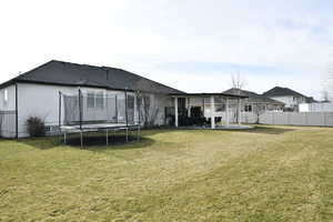 Rear view of house with a patio, a trampoline, and stucco siding