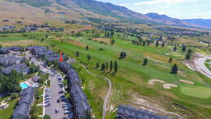 Aerial view of property's location featuring a golf club, a mountainous background, and nearby suburban area