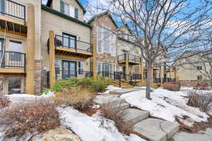 Snow covered house with stone siding and a balcony