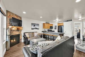 Living room featuring a stone fireplace, recessed lighting, and light wood-style flooring