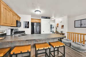 Kitchen featuring a peninsula, freestanding refrigerator, light wood finished floors, a kitchen breakfast bar, and light wood finish cabinets