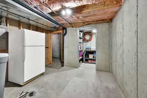 Unfinished below grade area with freestanding refrigerator and a water softener