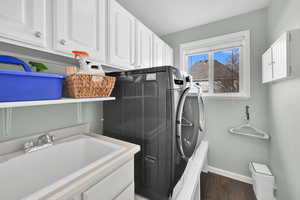 Laundry area with cabinet space, dark wood finished floors, and separate washer and dryer