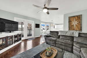 Living room featuring a ceiling fan, dark wood-style floors, and a textured ceiling