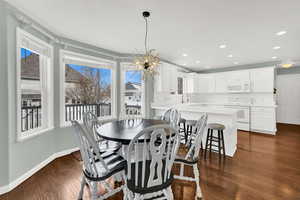 Dining space with a chandelier and dark wood-type flooring
