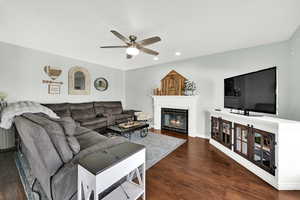 Living area featuring dark wood-type flooring, ceiling fan, a glass covered fireplace, and recessed lighting