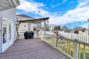 Wooden deck featuring a residential view, area for grilling, and a pergola