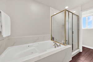 Full bathroom with a stall shower, a garden tub, and dark wood-type flooring