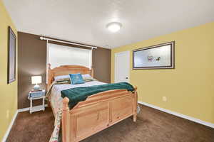 Bedroom featuring a textured ceiling and dark carpet