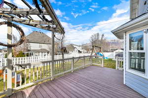 Wooden deck with a fenced backyard, a residential view, and a playground
