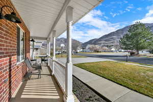 Covered porch featuring a mountain view, a residential view, and a lawn