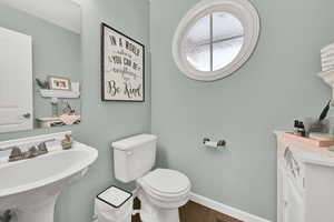 Half bath with toilet and wood finished floors