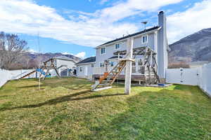 Back of property with a gate, a fenced backyard, a chimney, and a deck with mountain view