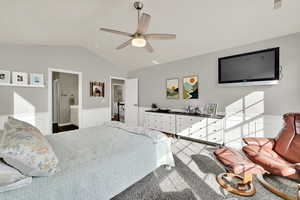 Bedroom featuring ceiling fan, a wainscoted wall, and ensuite bath