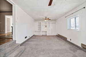 Unfurnished living room featuring a baseboard heating unit, a ceiling fan, and carpet