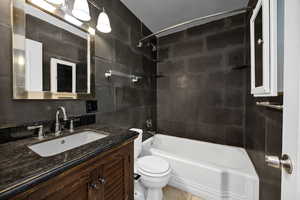Bathroom with shower / bathtub combination, vanity, and tile walls