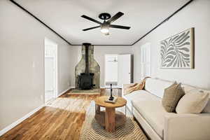 Living area with a wood stove, light wood-style flooring, and a ceiling fan