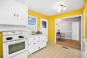 Kitchen featuring electric stove, white cabinets, light countertops, hanging lights, and light flooring