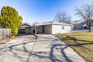 View of front of home with concrete driveway, a carport, and a patio area