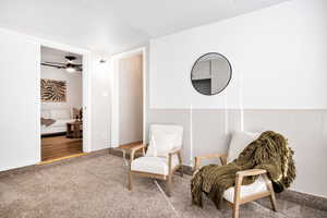 Sitting room featuring carpet floors, a ceiling fan, and wainscoting