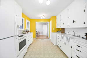 Kitchen with light flooring, white appliances, light countertops, and white cabinetry