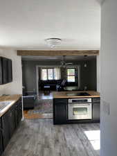Kitchen with dark cabinets, wooden counters, stainless steel oven, and decorative light fixtures