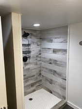 Full bathroom with tiled shower and recessed lighting