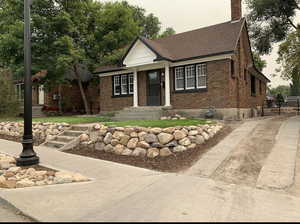 View of front of home featuring brick siding, a chimney, and a shingled roof