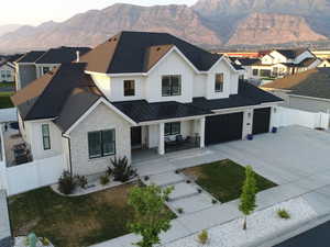 View of front of house with a porch, board and batten siding, driveway, a standing seam roof, and a residential view