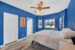 Primary Bedroom featuring laminate floors, ensuite bathroom, and ceiling fan