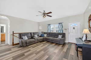 Great room featuring arched walkways, ceiling fan, and newer laminate floors