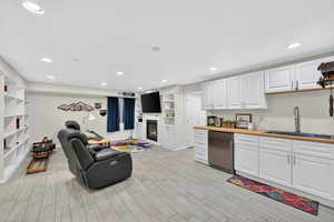 Kitchenette with white cabinetry, a glass covered fireplace, stainless steel refrigerator, open shelves, and butcher block countertops