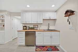 Kitchenette featuring white cabinets, stainless steel refrigerator and sink