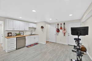 Kitchenette with stainless steel fridge, white cabinets, wood finish floors, recessed lighting, and butcher block counters