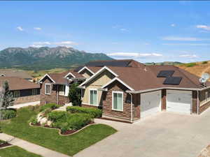 Craftsman-style home featuring solar panels, board and batten siding, driveway, an attached garage, and a mountain view